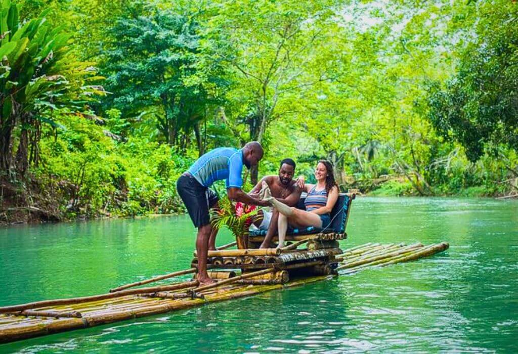 VibraGem Tours Bamboo Rafting and Limestone Massage Tour in Jamaica with a beautiful couple and a tour guide giving the lady a relaxing limestone foot massage.