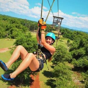 VibraGem Tours Zipline Tour in Jamaica with a female tourist ziplining with excitement.